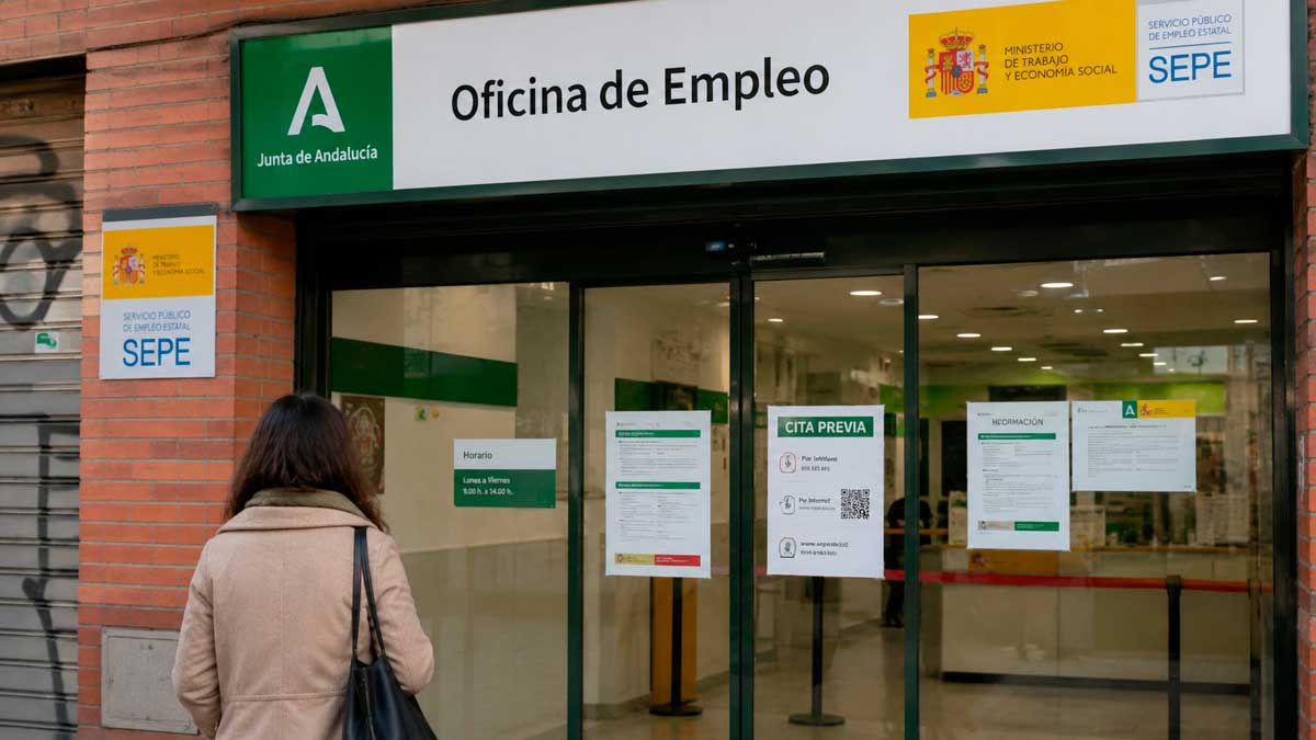 Mujer frente a una oficina del SEPE y la Junta de Andalucía para solicitar ayudas tras agotar el paro