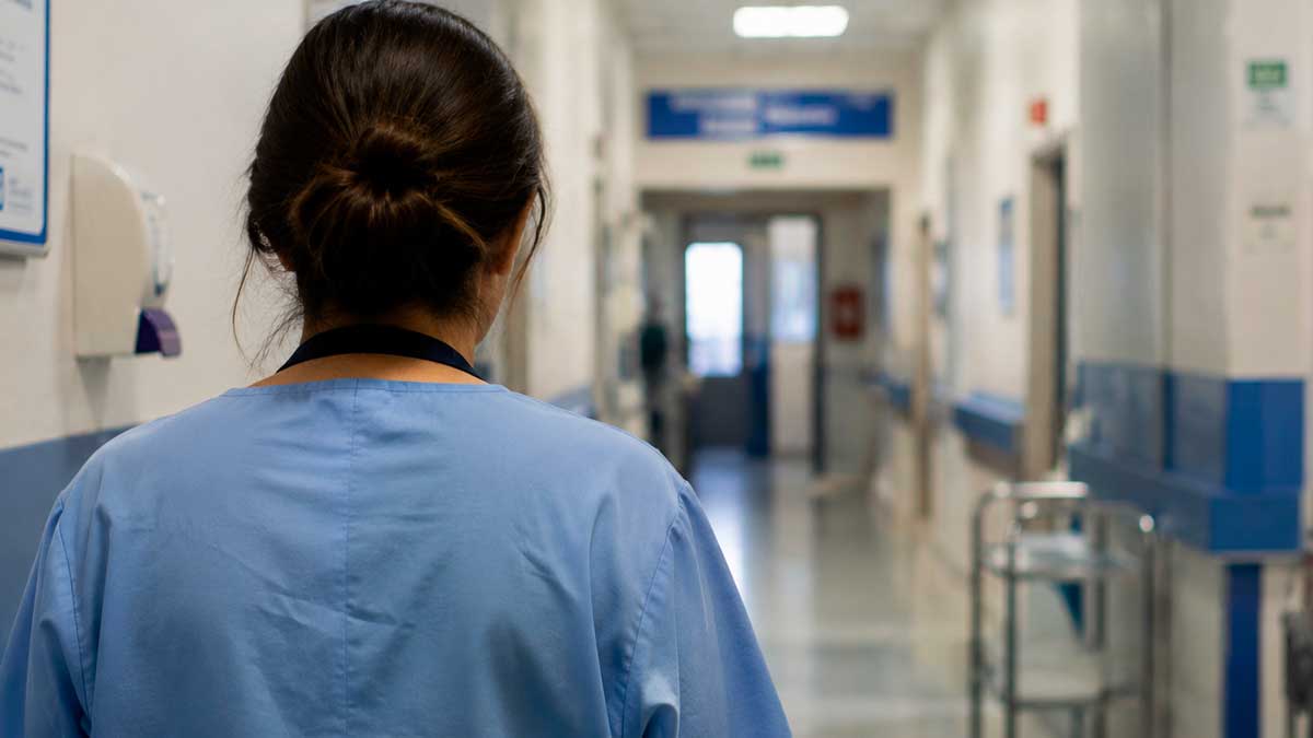 Trabajadora sanitaria de espaldas en un hospital tras una baja por ansiedad reconocida como accidente laboral