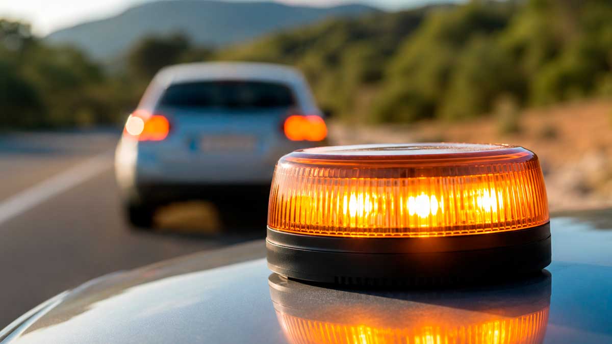 Baliza v16 conectada colocada sobre un coche averiado en carretera tras la advertencia de la DGT sobre modelos sin certificado vigente