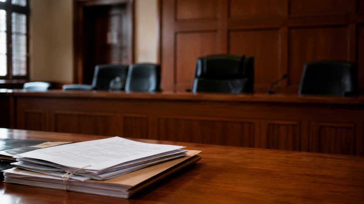 Sala de tribunal con documentos judiciales sobre una mesa por un caso de baja médica y devolución de prestaciones