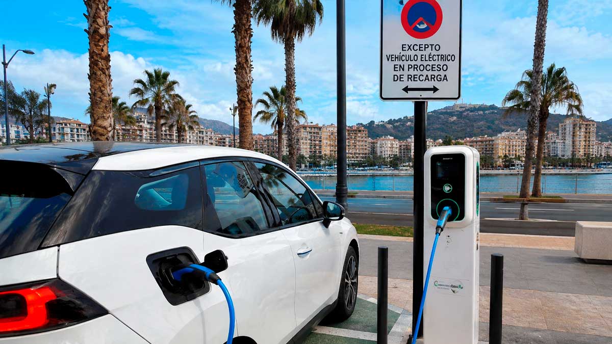 Coche eléctrico cargando gratis en un punto de recarga público frente al paseo marítimo de Málaga