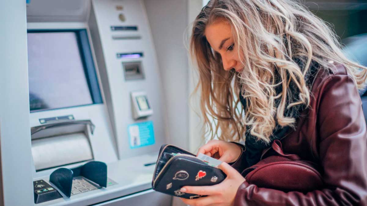 Mujer revisando dinero en cajero automático tras cobrar el paro en mayo de 2026