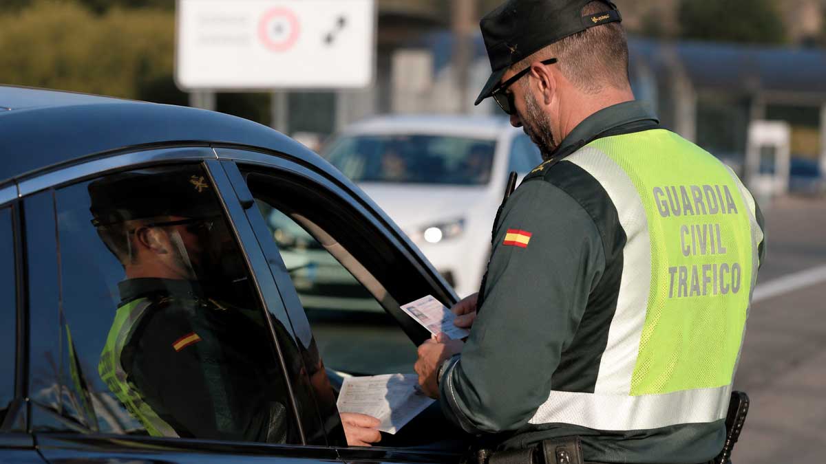 Agente de la Guardia Civil revisando la documentación obligatoria de un coche en un control de tráfico