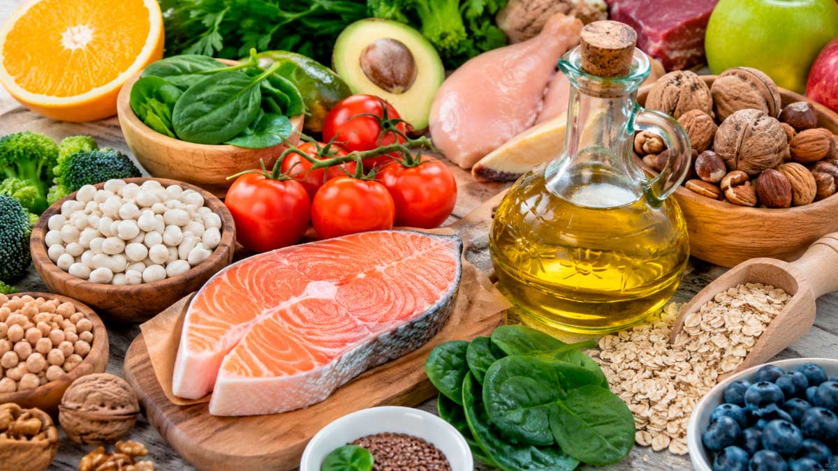 Alimentos recomendados para bajar el colesterol alto como salmón, aceite de oliva, frutos secos y verduras