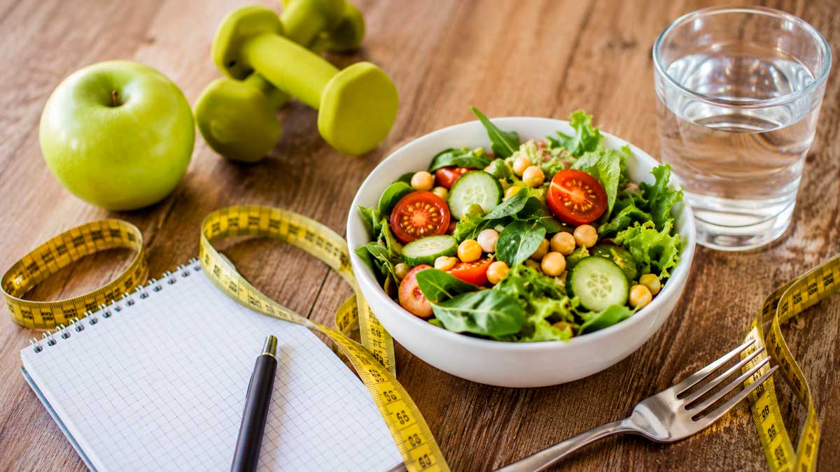 Ensalada saludable y cinta métrica representando los riesgos y beneficios de las dietas hipocalóricas para perder peso