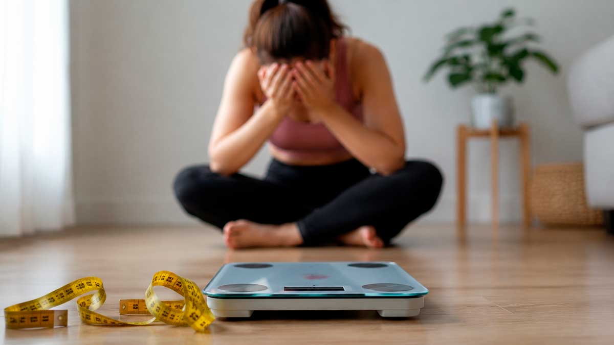 Mujer frustrada frente a una báscula tras no conseguir perder peso durante una dieta