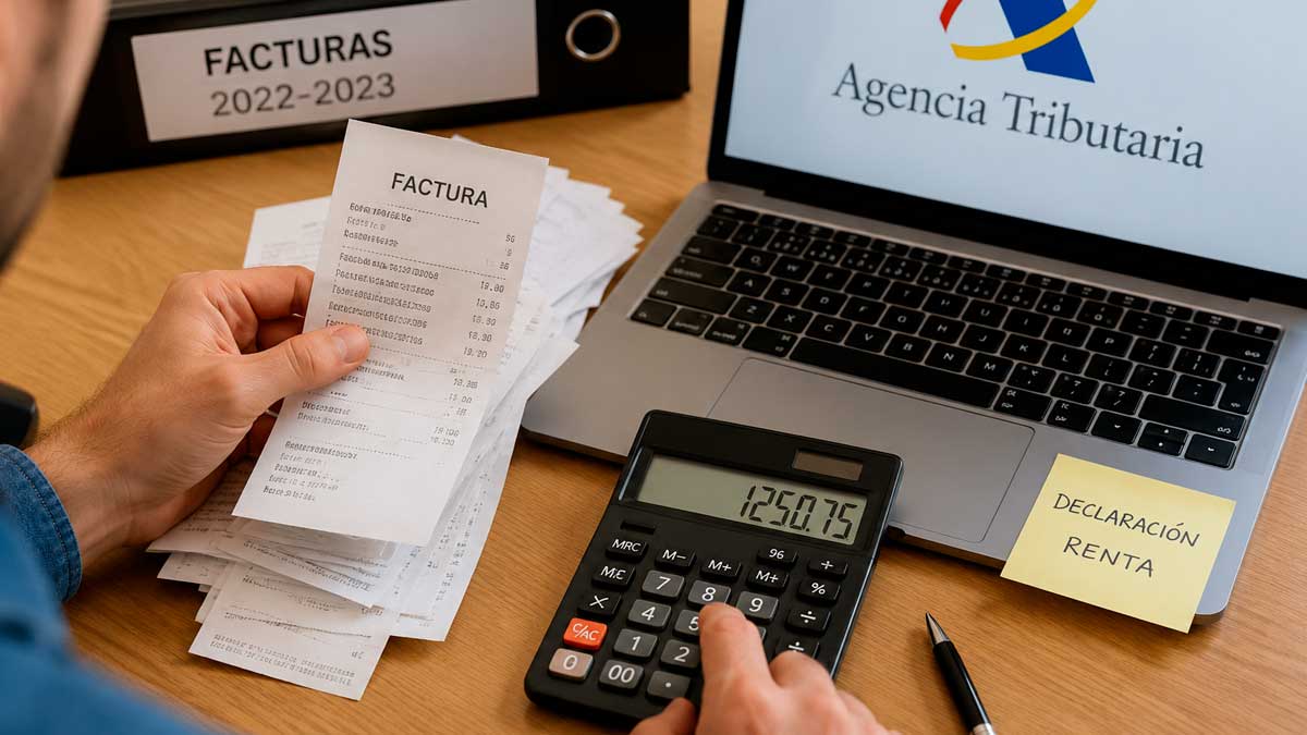 Autónomo revisando facturas atrasadas frente a un ordenador con la Agencia Tributaria durante la declaración de la Renta