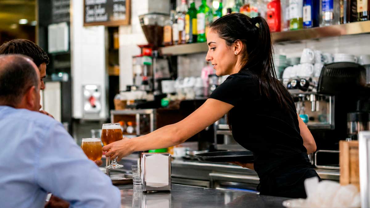 Camarera trabajando detrás de la barra de un bar mientras servía bebidas sin estar dada de alta en la Seguridad Social