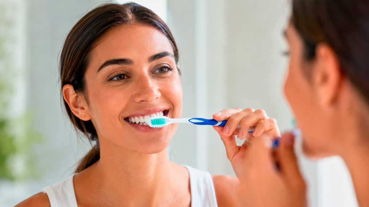 Mujer cepillándose los dientes para cuidar sus encías y evitar el sangrado dental
