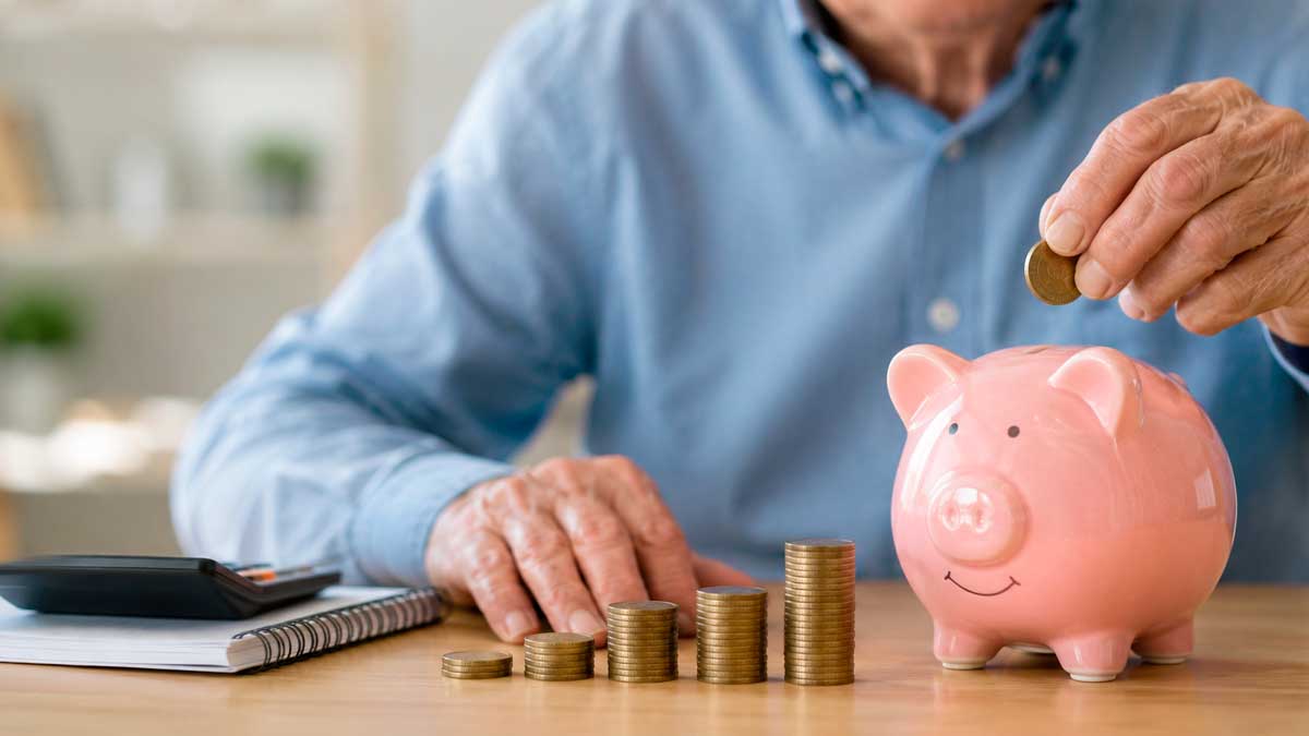 Persona mayor ahorrando dinero para la jubilación junto a una hucha tras conocerse la pensión con 25 años cotizados en 2026