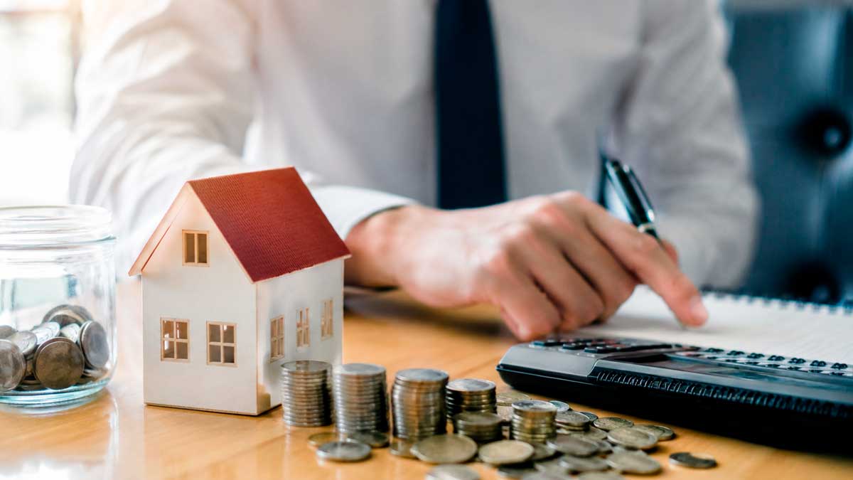 Vivienda en nuda propiedad junto a monedas y calculadora para explicar los gastos que debe asumir el propietario