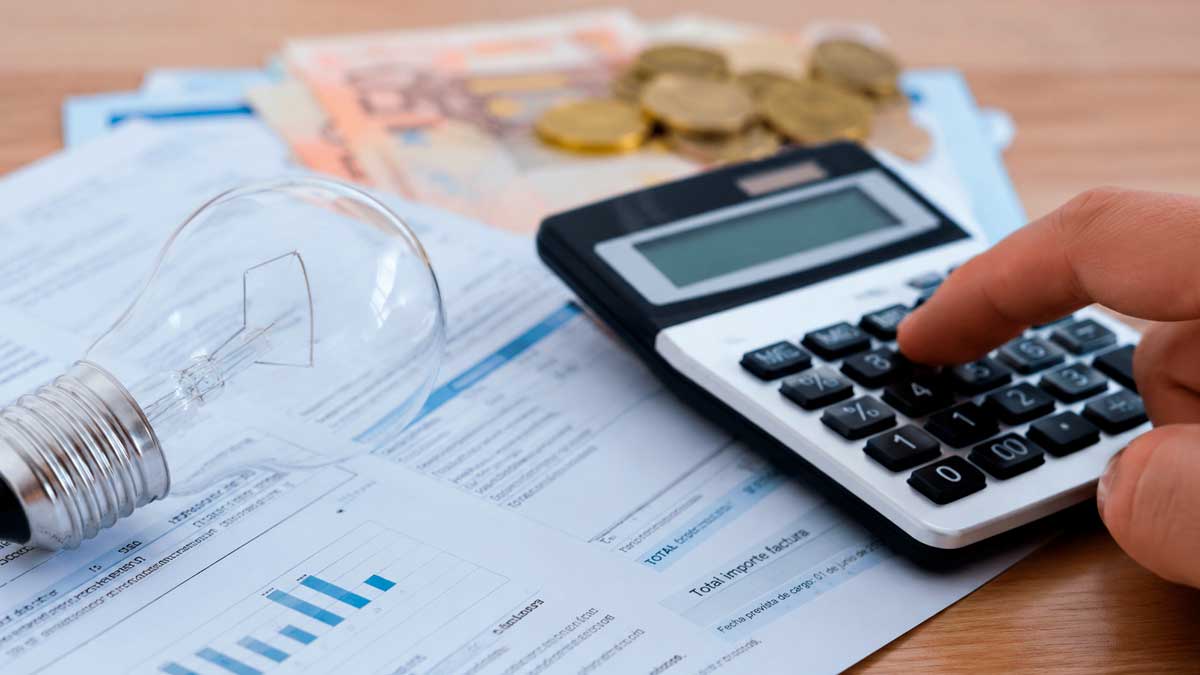 Factura de luz con calculadora y bombilla tras la subida del IVA de la electricidad y el gas