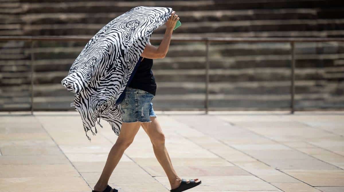 Persona protegiéndose del calor extremo en Málaga durante una jornada de altas temperaturas.