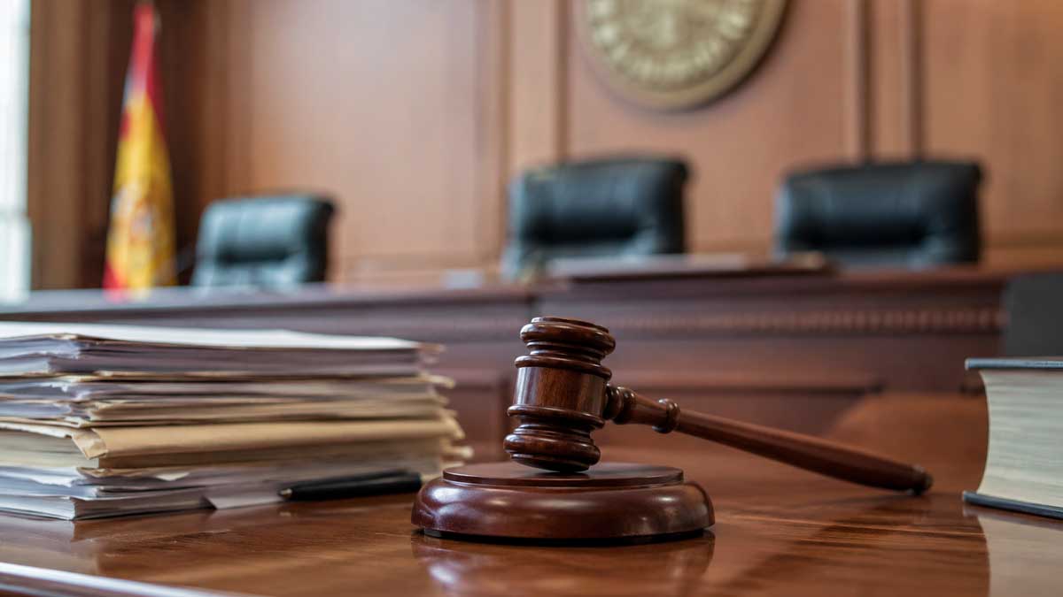 Sala de vistas con mazo judicial y documentos sobre una mesa durante un procedimiento relacionado con una incapacidad permanente