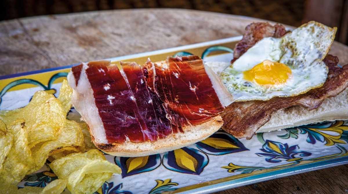 Tapa tradicional sevillana con jamón ibérico, carne y huevo en un bar histórico de Sevilla