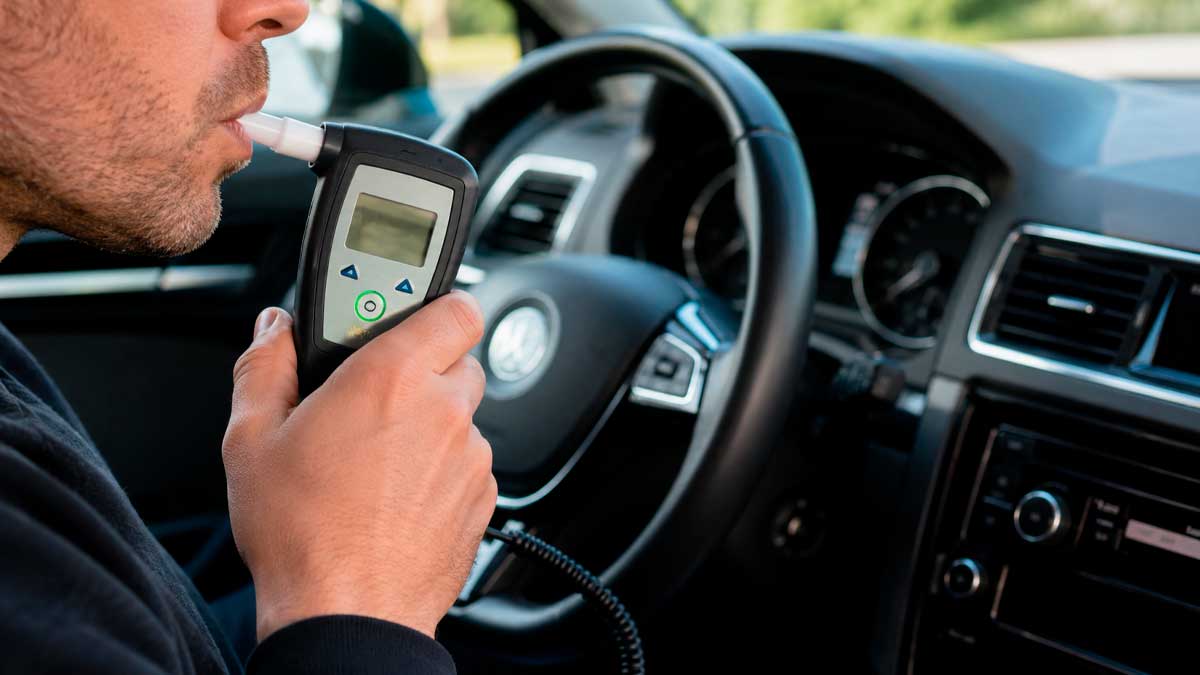 Conductor realizando una prueba de alcoholemia con un alcolock en el interior de un coche