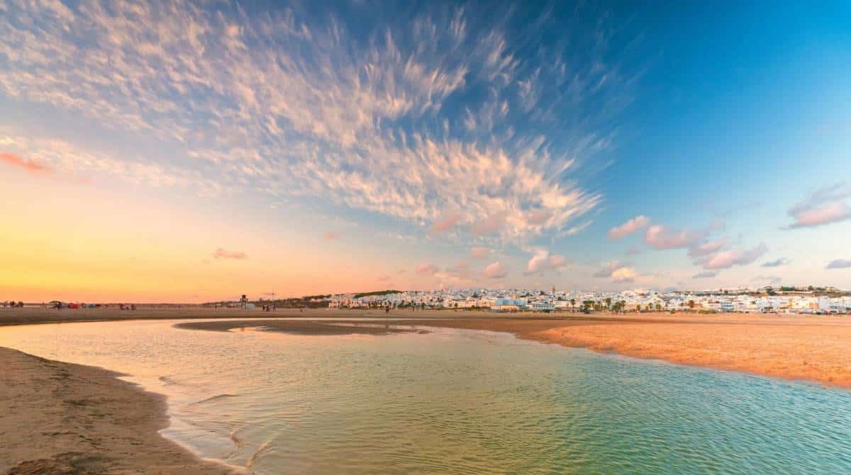 Conil de la Frontera al atardecer con su playa y el casco urbano al fondo en la costa de Cádiz