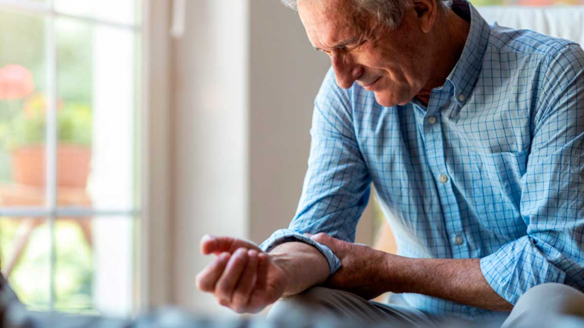 Hombre mayor con discapacidad del 33% en Andalucía sujetando su brazo y mostrando dolor
