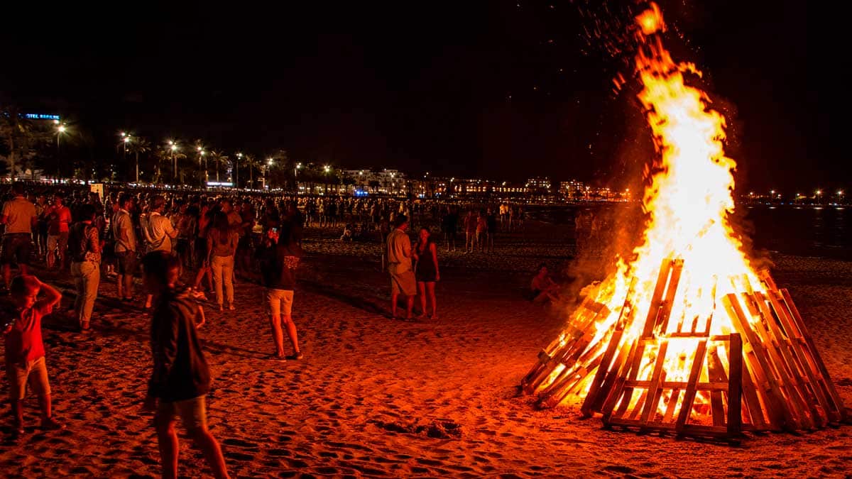 Noche de San Juan en Andalucía con hoguera en la playa y gente celebrando el festivo 2026