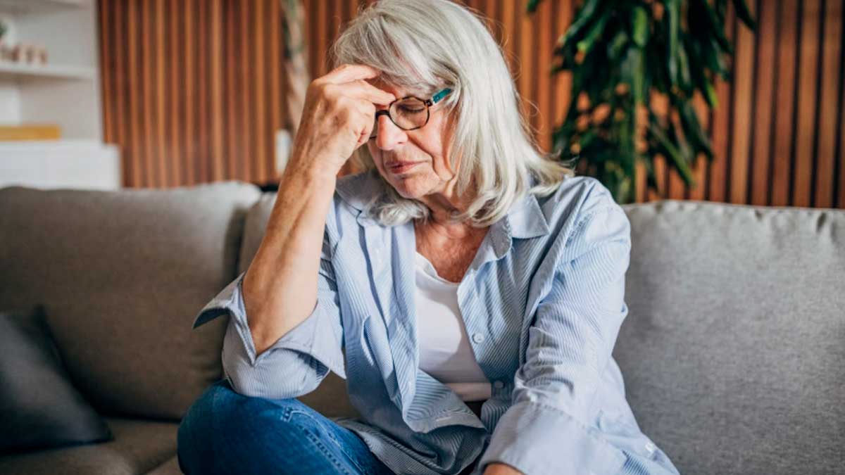 Mujer mayor de 45 años preocupada sentada en un sofá, reflejando el paro femenino en España