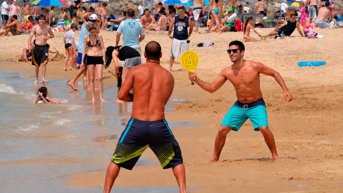 Jugadores de palas en una playa andaluza durante el verano rodeados de bañistas