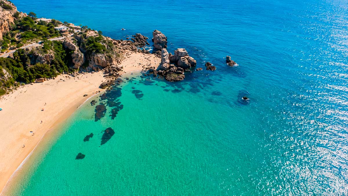 Vista aérea de una playa de aguas turquesas y arena clara en la costa de Andalucía