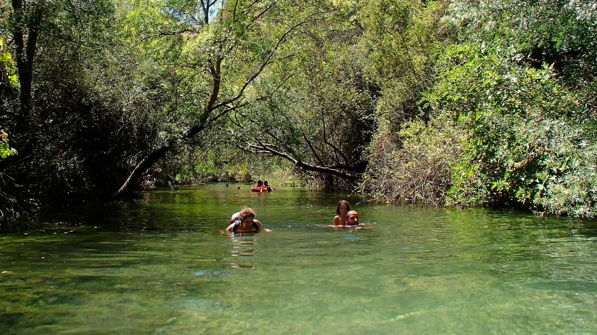 Piscina natural del río Turón en Málaga rodeada de vegetación durante una ruta de senderismo en junio