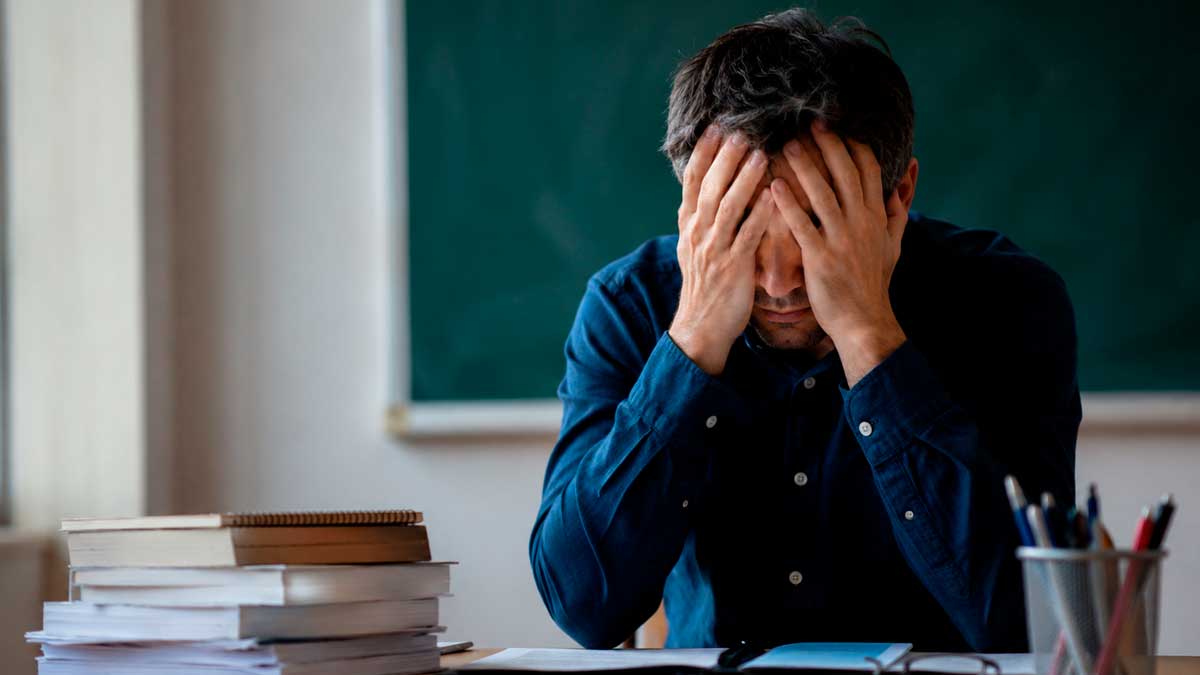 Profesor sentado en un aula con signos de estrés tras una sentencia del TSJ de Andalucía sobre depresión y accidente laboral Caption (pie de foto)