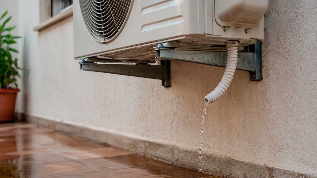 Agua goteando del tubo de desagüe de un aire acondicionado instalado en la fachada de una vivienda.