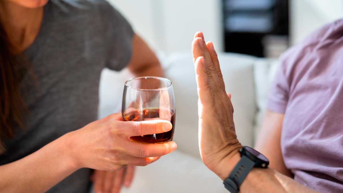 Persona rechaza una copa de alcohol en la vejez, riesgos de salud y efectos agravados en verano