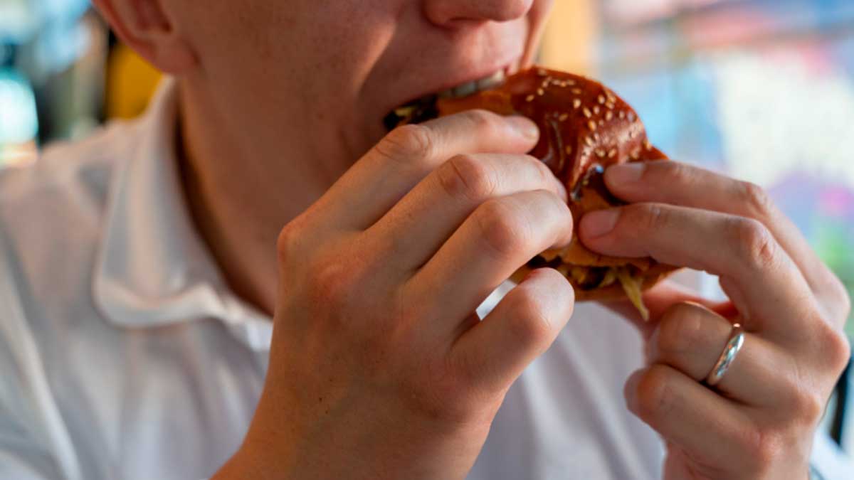 Persona comiendo un alimento ultraprocesado, relacionado con riesgos para la salud y la atención