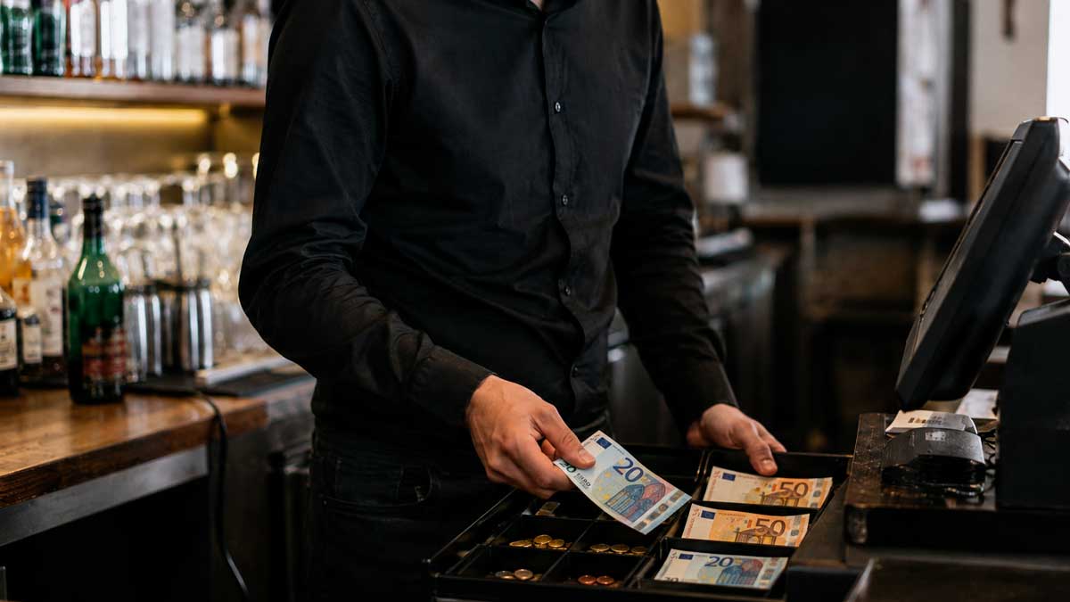 Camarero contando billetes en la caja registradora de un bar en Granada por apropiación indebida