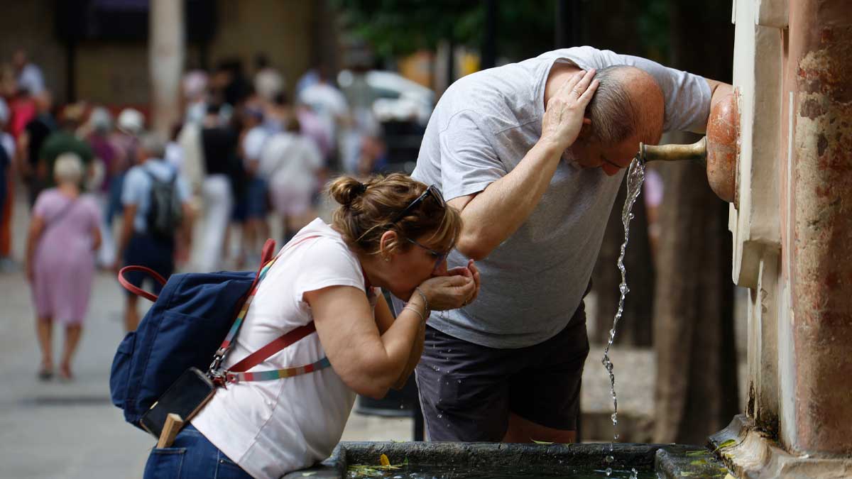 Personas se refrescan en una fuente pública durante la ola de calor en Andalucía