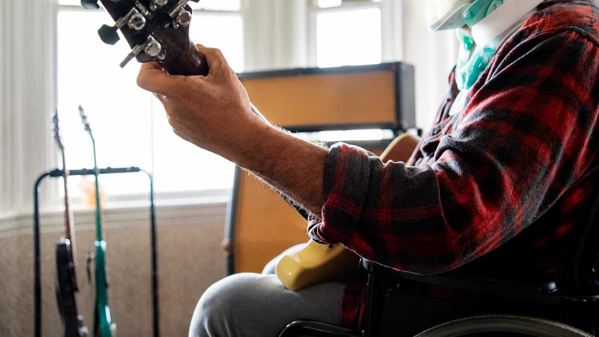 Persona en baja laboral tocando la guitarra en silla de ruedas, baja laboral