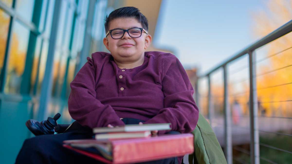 Joven investigador con discapacidad sonríe en silla de ruedas, becas Fundación ONCE