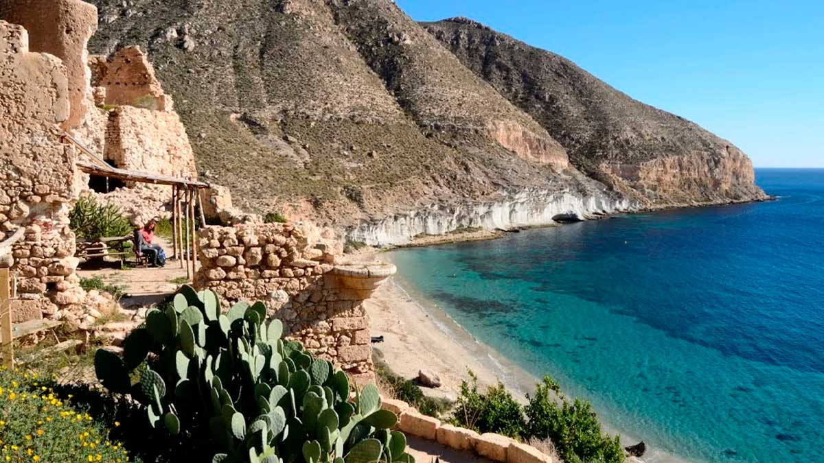 Cala de Almería con aguas cristalinas, casas de piedra y un histórico asentamiento hippie junto al mar