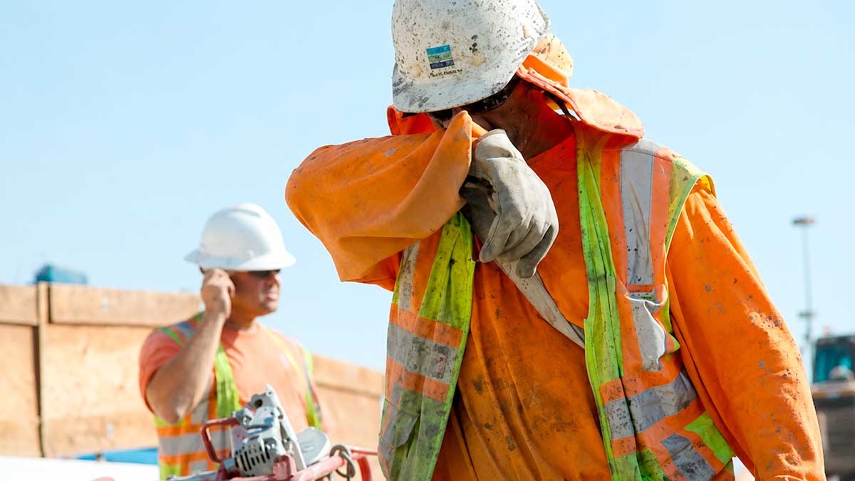 Trabajadores de la construcción afectados por el calor en el trabajo con ropa de alta visibilidad