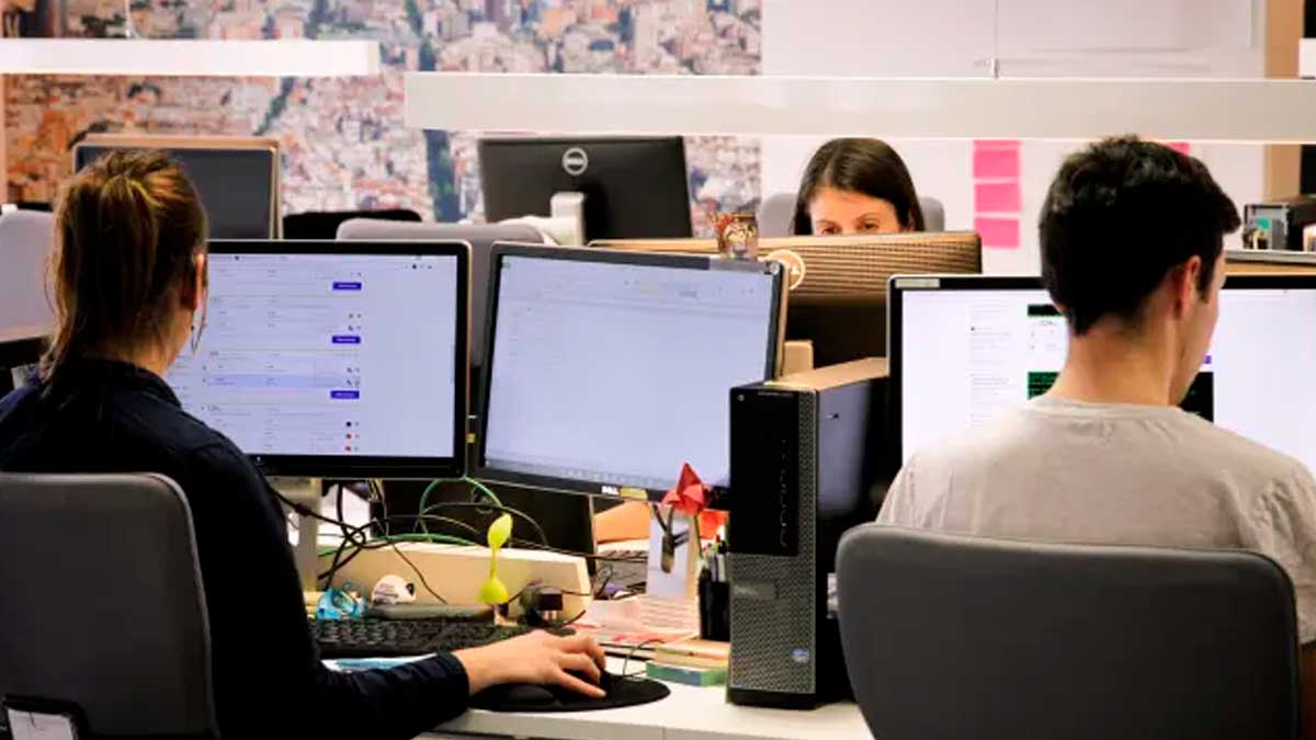 Personas trabajando en una oficina ante varios ordenadores