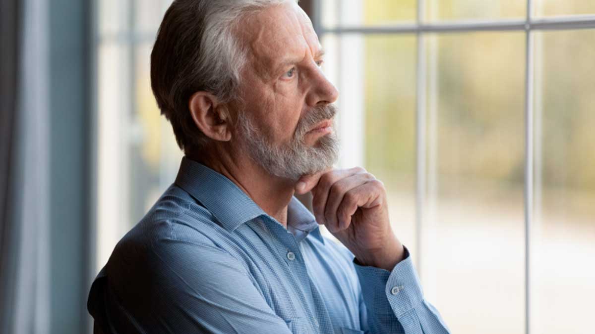 Hombre mayor pensativo mirando por la ventana, discriminación por edad en el trabajo en España