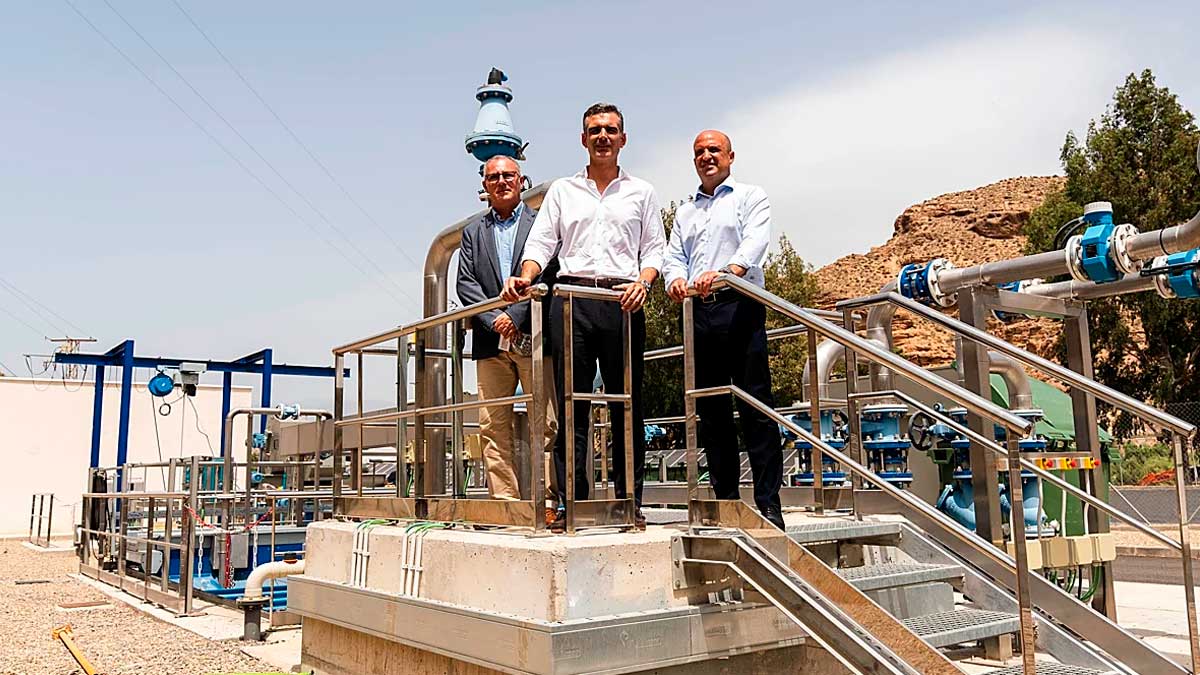 En la imagen, tres responsables posan sobre la plataforma principal de la nueva planta de depuración EDAR de Alhama, rodeados de infraestructuras hidráulicas y equipos técnicos. El entorno muestra instalaciones modernas y un paisaje natural al fondo, destacando la importancia de la obra para la gestión del agua en la comarca.