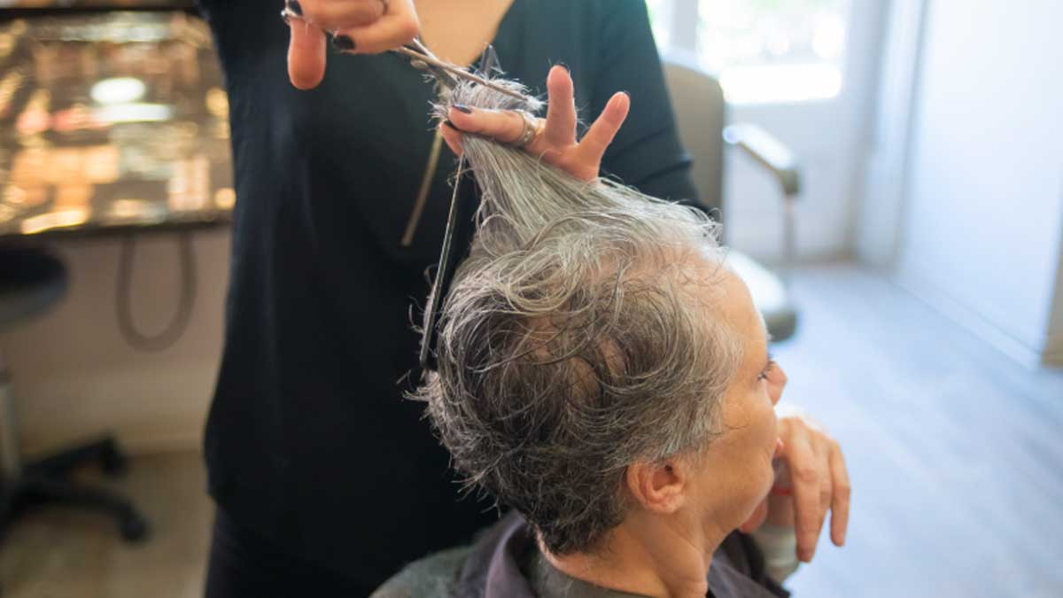 Peluquera cortando el pelo a una persona mayor en residencia privada, extras en residencias privadas