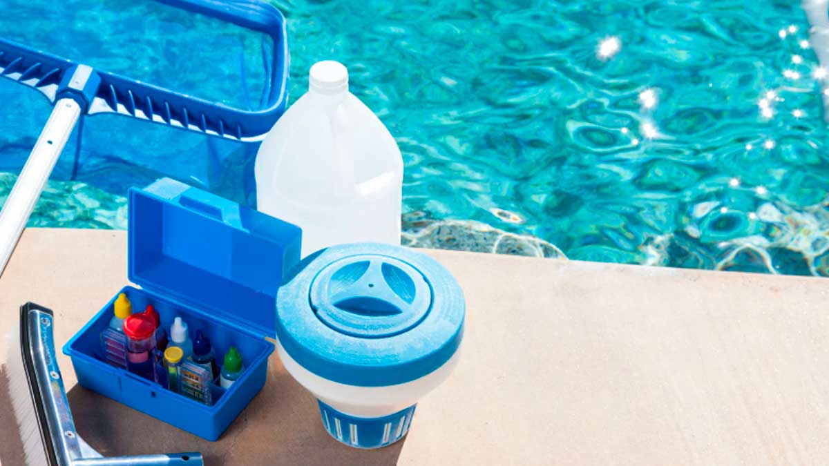 Kit de mantenimiento de piscinas con productos químicos y herramientas junto a una piscina en verano