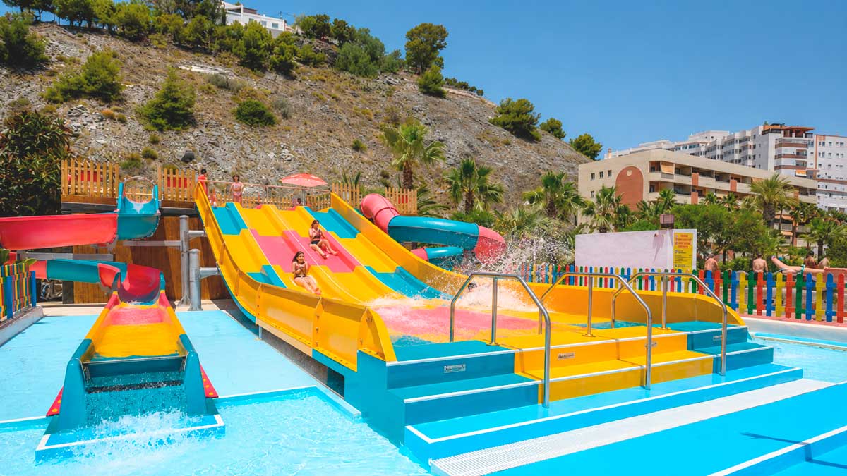 Toboganes de colores en el parque acuático Aquatropic con visitantes disfrutando, tarifas y novedades 2026