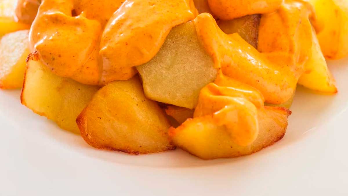 Patatas mozárabes con salsa, la tapa sevillana tradicional servida en plato blanco