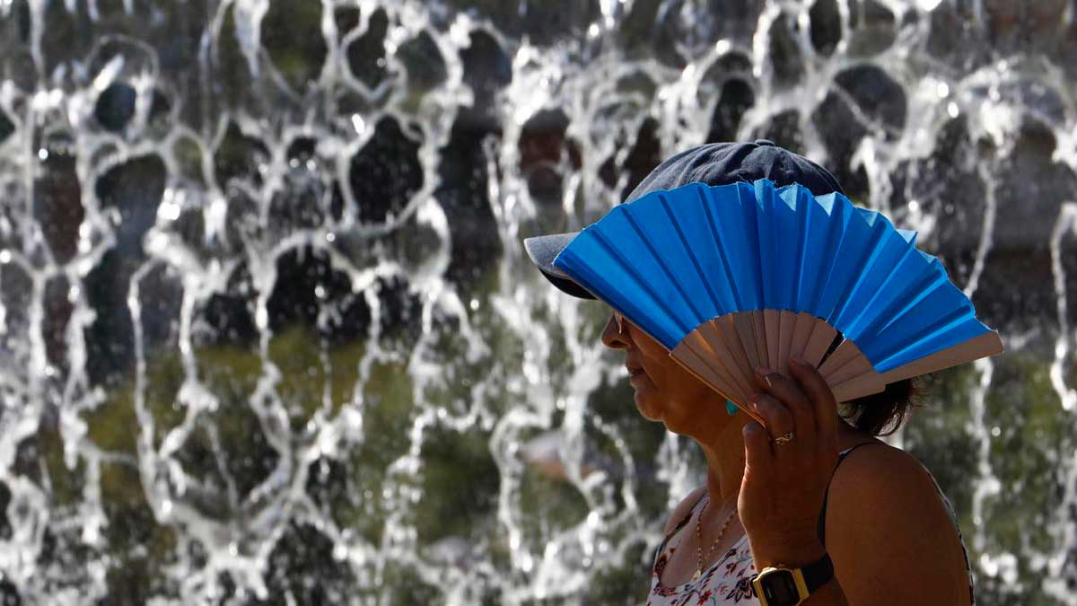 Persona con abanico azul se protege del calor en Jaén durante aviso naranja por altas temperaturas