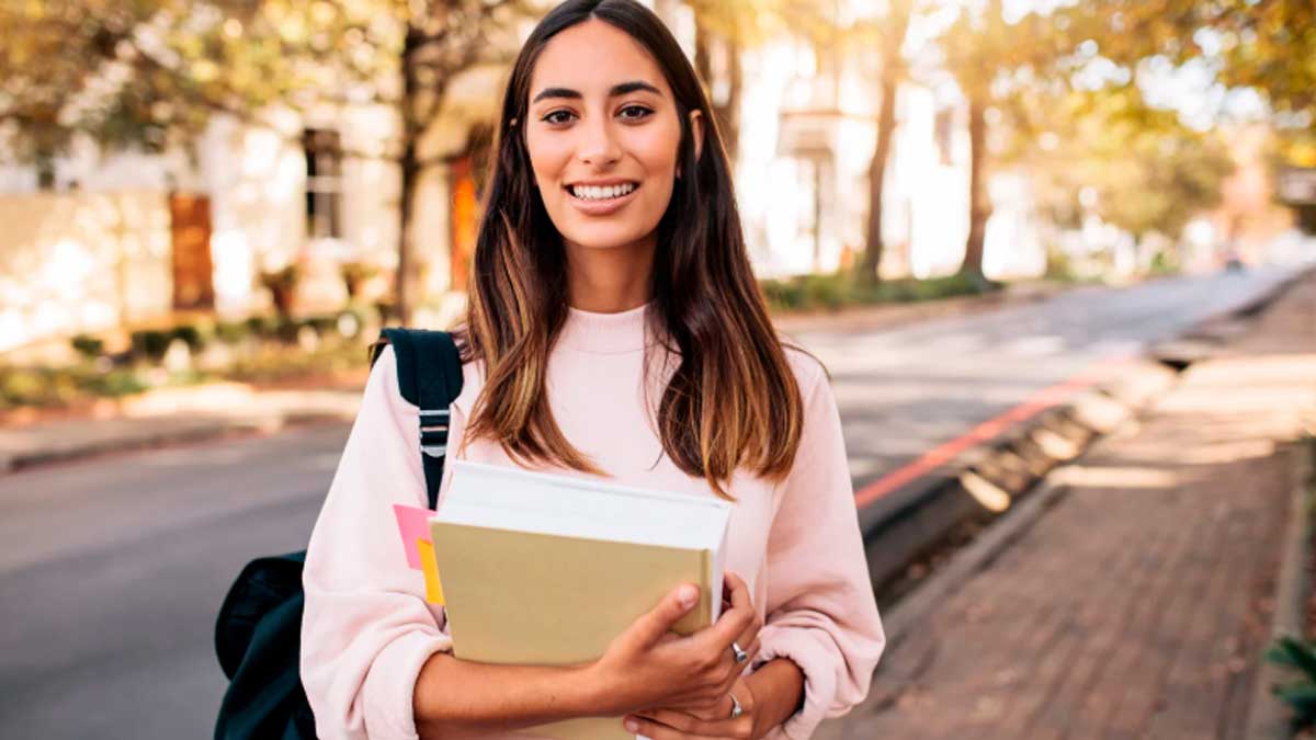 Estudiante joven con libros recibe ayudas para acreditar idiomas en Andalucía