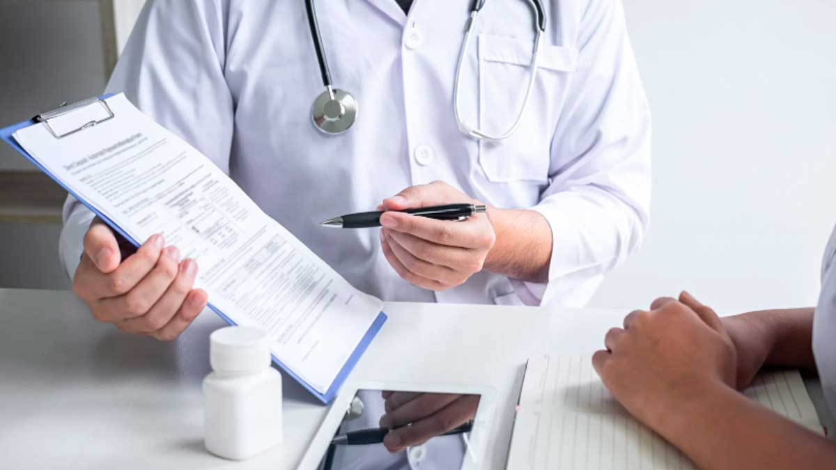 Médico explicando baja médica y vacaciones a paciente con documentos en consulta