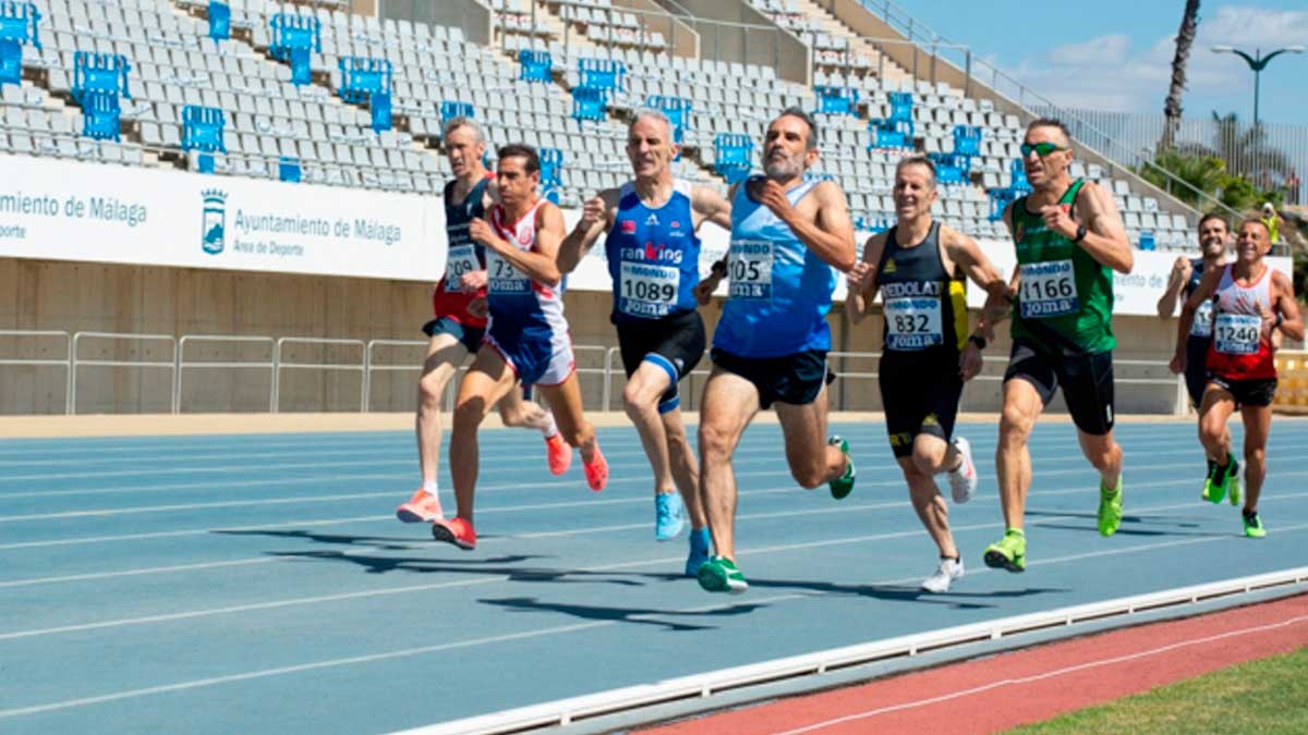 Atletas compitiendo en pista durante una carrera en Málaga, becas para deportistas individuales