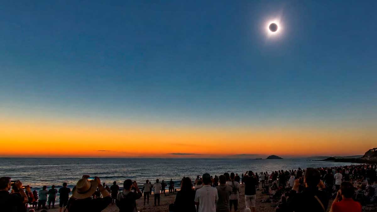 Eclipse solar de 2027 visto desde la playa de Cádiz con turistas observando el fenómeno