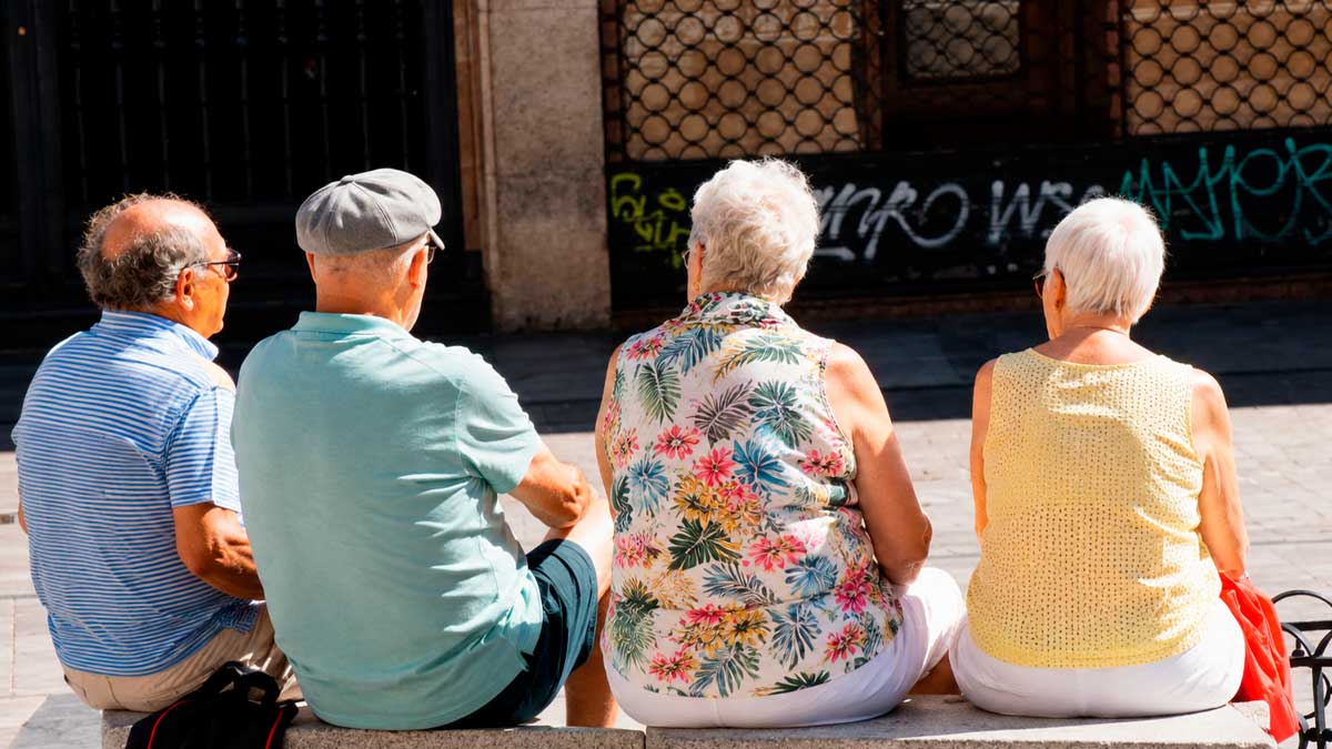 Personas mayores sentadas en un banco en la calle, edad de jubilación a los 67 años